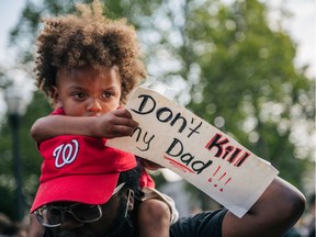 A boy sits on his fathers shoulders while holding a sign on August 24, 2020 in Kenosha, Wisconsin. A night of civil unrest occurred after the shooting of Jacob Blake, 29, on August 23. Blake was shot multiple times in the back by Wisconsin police officers after attempting to enter into the drivers side of a vehicle.