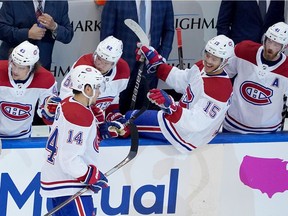 The Canadiens’ Jesperi Kotkaniemi (15) leans over the boards at bench to congratulate Nick Suzuki (14) after he scored a goal during Game 1 of NHL postseason qualifying series against the Pittsburgh Penguins at Toronto’s Scotiabank Arena.