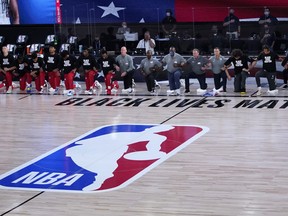 Washington Wizards, left, and the Milwaukee Bucks, right, kneel prior to the first half of an NBA basketball game, Tuesday, Aug. 11, 2020, in Lake Buena Vista, Fla. at Visa Athletic Center.