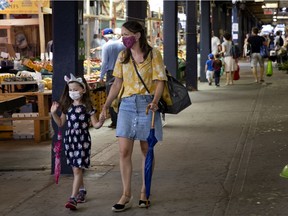 Marie-Helene Paquette and her daughter Romi stay out of the rain as they walk the Atwater Market in Montreal, on Sunday, August 2, 2020. (Allen McInnis / MONTREAL GAZETTE) ORG XMIT: 64812