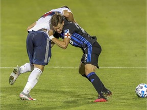 Montreal Impact defender Jukka Raitala holds Vancouver Whitecaps forward Lucas Cavallini during an MLS game in Montreal Aug. 25, 2020.