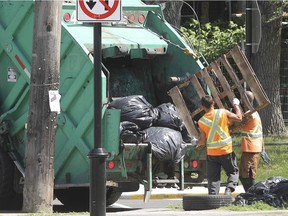 Workers place items in a garbage truck.
