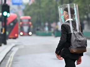 A pedestrian wearing a a a full-face covering as a precautionary measure against COVID-19 walks across Oxford St. in central London on June 11, 2020.