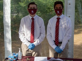 Loyola High School students, Alessandro Vani and Daniel Magee, assisting with the school's drive-in convocation earlier this summer.