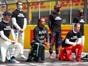Mercedes' British driver Lewis Hamilton (C) and fellow drivers make a statement on the track as they 'take a knee' in support of the Black Lives Matter movement, prior to the start of the Formula One British Grand Prix at the Silverstone motor racing circuit in Silverstone, central England on Aug. 2, 2020.