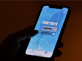 This illustration picture shows a person waiting for an update of Epic Games' Fortnite on their smartphone in Los Angeles on August 14, 2020. - Apple and Google on August 13, 2020 pulled video game sensation Fortnite from their mobile app shops after its maker Epic Games released an update that dodges revenue sharing with the tech giants. (Photo by Chris DELMAS / AFP)