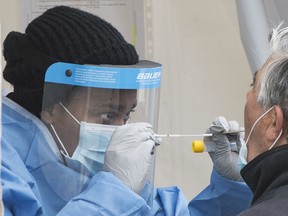 A health-care worker prepares to swab a man at a walk-in COVID-19 test clinic in Montreal North, Sunday, May 10, 2020. Four philanthropic foundations are collaborating to provide emergency interim funding to immediately mobilize neighbourhoods that have been hardest hit by COVID-19, including Montreal North.