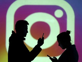 Silhouettes of mobile users are seen next to a screen projection of Instagram logo in this picture illustration taken March 28, 2018.  REUTERS/Dado Ruvic/Illustration/File Photo