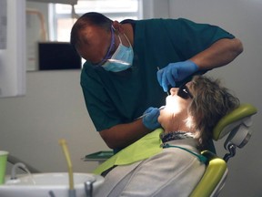 FILE PHOTO: A dentist tends to a patient at Silveroaks Dental Surgery as it opens for non aerosol generating assessments in Milton Keynes, following the outbreak of the coronavirus disease (COVID-19), Milton Keynes, Britain, June 8, 2020. REUTERS/Andrew Boyers/File Photo