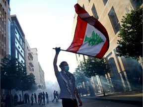 A demonstrator waves a Lebanese flag during anti-government protests that have been ignited by a massive explosion in Beirut, Lebanon August 10, 2020.