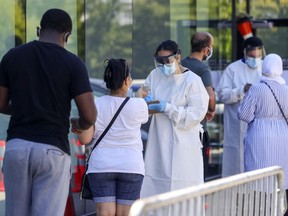 People are screened while in line at a COVID-19 testing centre in the Montreal area Aug. 6, 2020.