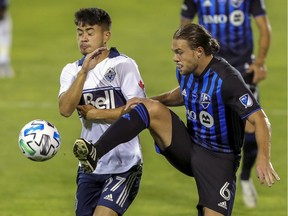 Montreal Impact midfielder Samuel Piette, right, and Vancouver Whitecaps midfielder Ryan Raposo compete for a loose ball during MLS game in Montreal on Aug. 25, 2020.