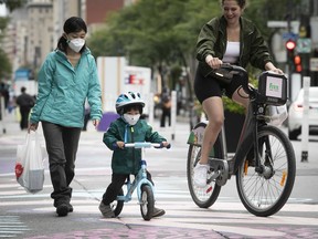 Four year-old Ziqi Qiang, with his bike and mother Yuexin Lyu, left, make their way along Ste-Catherine near Mackay with other cyclist using the sanitary corridor in the downtown core on Tuesday September 1, 2020. (Pierre Obendrauf / MONTREAL GAZETTE)