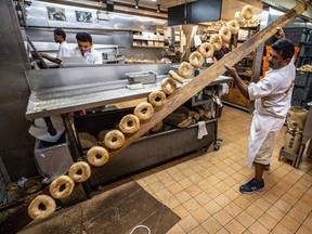 Baker Sathees Senarajah tosses another row of finished bagels into a basket at Fairmount Bagel on Sept. 5, 2019.
