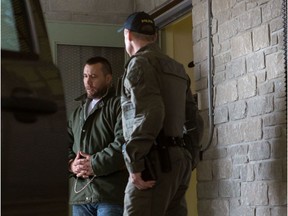 An OPP officer escorts Jean-François Emard out of the courthouse in L'Orignal, Ont., following his bail hearing on May 2, 2016.