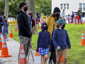 Olivier Thibodeau and Aislinn Maxwell wait in line with their children — Billy (right) and Loïe — for COVID-19 testing in the Outremont borough of Montreal on Wednesday.