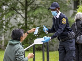 A security guard hands out masks and hand sanitizer outside the COVID-19 testing centre in the Outremont borough of Montreal Wednesday September 9, 2020. (John Mahoney / MONTREAL GAZETTE)