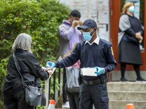 A security guard gives a woman a squirt of hand sanitizer outside the Covid-19 testing centre in the Outremont borough of Montreal Wednesday September 9, 2020.