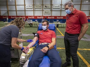 Laval Rocket head coach Joël Bouchard watches as assistant coach Daniel Jacob gives blood at the 47th edition of the Laval resident's blood drive in Laval on Sept. 11, 2020.