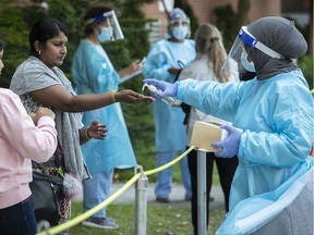 Nurses help with hand sanitizers and take information from people waiting in line for COVID-19 at the Parc-Extension CLSC on Wednesday, September 16, 2020.