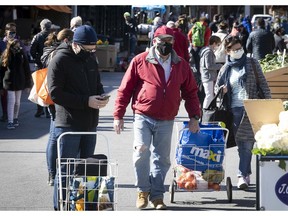 People with their faces covered with masks walk along Jean-Talon market on Sunday September 20, 2020.