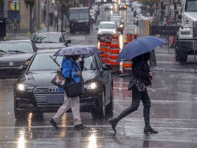 Pedestrians battle the  rain while walking on  René-Lévesque Blvd. on Tuesday. Montreal's downtown core will once again be hit hard by the city's latest measures to control the novel coronavirus.