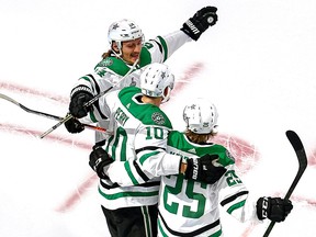 Anton Khudobin (35) of the Dallas Stars is congratulated by Corey Perry (10) and Roope Hintz (24) after scoring a goal against the Tampa Bay Lightning during the second period in Game 1 of the 2020 NHL Stanley Cup Final at Rogers Place on Saturday, Sept. 19, 2020.