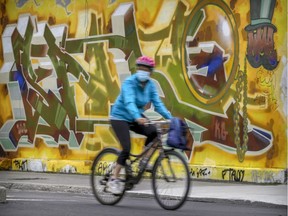 A mask-wearing cyclist rides by a mural in Mile End on Wednesday.