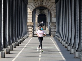 A woman wears a protective mask as she jogs, in Paris, on March 28, 2020. "When it comes to marathons, we know they require proper training, conditioning, preparation and the right headspace. This ongoing battle against COVID-19 is not so different," Fariha Naqvi-Mohamed writes.