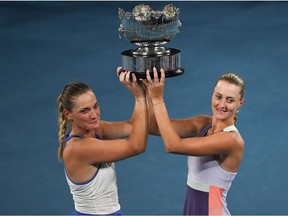 In this file photo taken on Jan. 31, 2020, Hungary's Timea Babos, left, and France's Kristina Mladenovic pose with the championship trophy during the awards ceremony after their victory against Taiwan's Hsieh Su-wei and Czech Republic's Barbora Strycova during the women's doubles final on day twelve of the Australian Open tennis tournament in Melbourne. The U.S. Open was plunged into controversy on Saturday, Sept. 5, 2020, after New York health officials ordered the women's top doubles pairing of Mladenovic and Babo be withdrawn from the tournament because of the possible exposure to coronavirus. The pair was instructed to quarantine for coming in contact with Benoît Paire, who tested positive for COVID-19 last weekend.