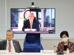 President of the Tokyo 2020 Organising Committee Yoshiro Mori (L) and Tokyo governor Yuriko Koike (R) listen as  International Olympic Committee (IOC) president Thomas Bach (on screen) speaks during a video meeting of the IOC Coordination Commission for the Tokyo 2020 Olympic Games in Tokyo on September 24, 2020.