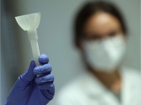 A laboratory worker shows a prototype of a self-test that uses saliva in a rapid COVID-19 test in this file photo.