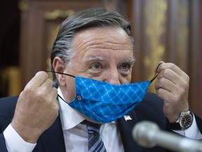 Quebec Premier Francois Legault pulls his mask off as he arrives at a legislature committee studying his office budget spending, Wednesday, August 19, 2020 at the legislature in Quebec City.