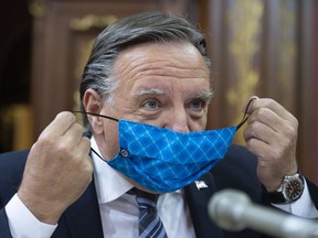 Quebec Premier François Legault pulls his mask off Aug. 19, 2020.