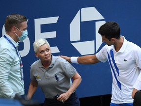 Novak Djokovic, right, and a tournament official tend to a linesperson who was struck with a ball by Djokovic against Pablo Carreno Busta on Day 7 of the 2020 U.S. Open at USTA Billie Jean King National Tennis Center in Flushing Meadows, N.Y., on Sunday, Sept. 6, 2020.