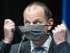 Quebec Finance Minister Éric Girard removes his face mask as he arrives for a news conference Friday, Sept. 25, 2020 in Montreal.