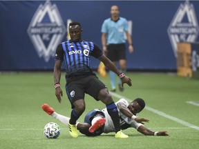 Impact midfielder Victor Wanyama, standing, battles Whitecaps midfielder Cristian Dajome for the ball during first-haf action at B.C. Place Wednesday night.