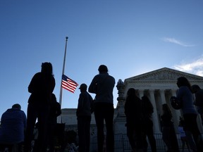 The U.S. flag is seen at half-mast as people gather in front of the U.S. Supreme Court following the death of Justice Ruth Bader Ginsburg, in Washington, D.C., September 19, 2020.