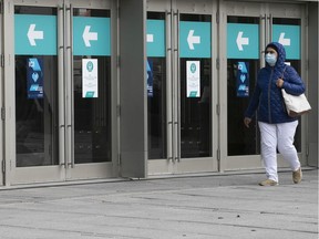 A woman walks past restricted doors at the entrance to a downtown shopping mall Sept. 30, 2020.