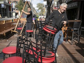 Bobby Choudhry, left, and Danny Lalonde take down plexiglass partitions and stow chairs from the outdoor terrace at Le Date bar in Montreal's Gay Village on Oct. 1, 2020