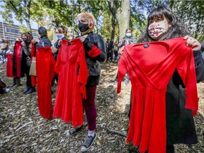 Women hold up red dresses signifying murdered and missing Indigenous women during "Justice for Joyce Echaquan" demonstration in Montreal on Saturday, Oct. 3, 2020.