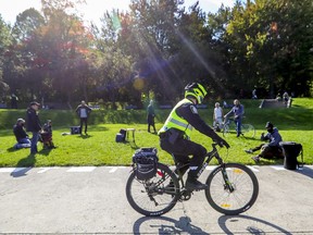 A Montreal police officer rides past a group of physically distanced drummers near the George-Étienne Cartier Monument in Mount Royal Park in Montreal Oct. 4, 2020.