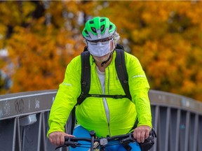 A mask wearing man rides his bike through Montreal on Monday, Oct. 5, 2020.