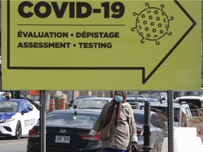 Making her way down Côte-des-Neiges Rd., a woman walks past a sign for COVID testing at the Jewish General Hospital on Thursday, Oct. 8, 2020.