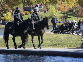 Masked mounted police ride their horses along the path on Beaver lake as people enjoy the sunny autumn day at Mount Royal on Monday October 12, 2020.