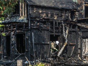 A firefighter examines the charred remains of a blaze at a Laval home that killed a 19-year-old woman.