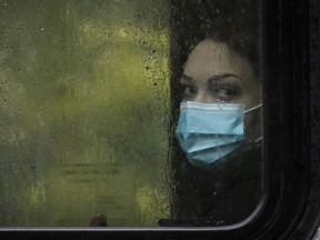A woman looks out a rain drenched bus window on Sherbrooke street  in downtown Montreal on Oct. 13, 2020