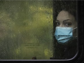 A woman looks out a rain-drenched bus window in downtown Montreal on Tuesday, Oct. 13, 2020.