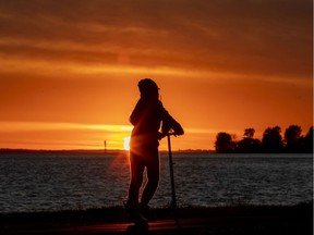 A young girl pushes her scooter on the walking path along the lakeshore at sunset in the Lachine borough of Montreal on Wednesday, October 14, 2020.