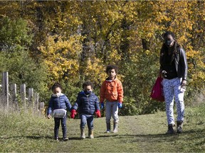 Wendy Simpson enjoys a scenic autumn walk at Cap St. Jacques ecological farm in Pierrefonds with her kids Aaron (orange) and Isaac, centre, and their cousin Celeste Simpson-Fortin, on Saturday, Oct. 17, during the COVID-19 pandemic.